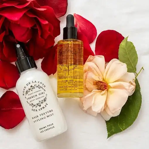 Two bottles of beauty products surrounded by red and pink flowers on a white background